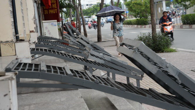 Nhà cao hơn vỉa hè đường Phạm Văn Đồng (P.1, Q.Gò Vấp) gần 1m nên người dân lắp thêm những tấm sắt để dẫn xe máy lên nhà làm mất vẻ mỹ quan đô thị và gây nguy hiểm cho khách bộ hành - Ảnh: TỰ TRUNG