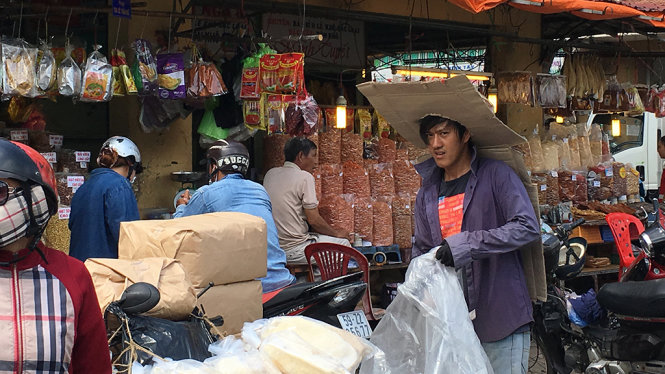 Anh Út , bốc xếp chợ Bình Tây, quận 6 TP.HCM chống chọi với nắng nóng bằng sáng kiến lấy thùng mì gói làm nón đội kéo dài đến lưng - Ảnh Tự Trung