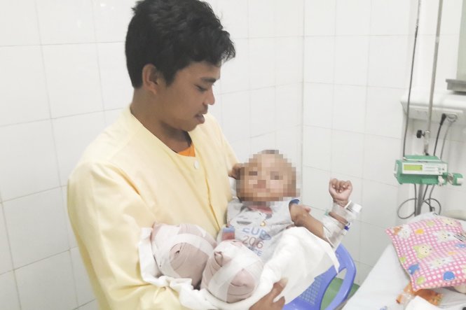 Bé Quốc Quân trong vòng tay cha - Ảnh: Tấn Lực