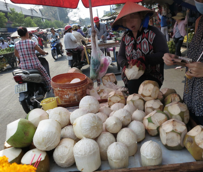Hiện nay vẫn còn tình trạng tiểu thương sử dụng chất cấm để xử lý thực phẩm. Trong ảnh: người bán nhúng dừa vào chất tẩy trắng - Ảnh: T.T.D.