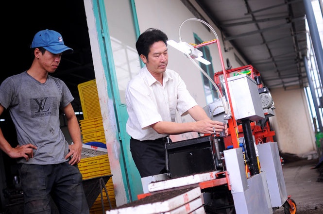 Anh Nguyễn Hồng Chương (phải) điều chỉnh chiếc máy gieo hạt chân không “6 trong 1” tự động của mình - Ảnh: LÂM THIÊN
