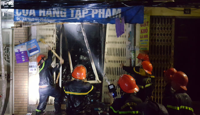 Lực lượng Cảnh sát PCCC đang phá cửa và phun nước dập lửa ở khu vực tầng 1 của ngôi nhà - Ảnh: Thường Văn