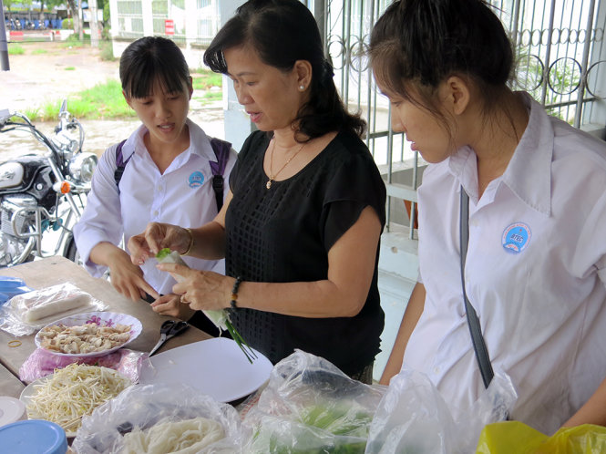 Cô giáo đang hướng dẫn học sinh làm bì cuốn - Ảnh: T.Trang