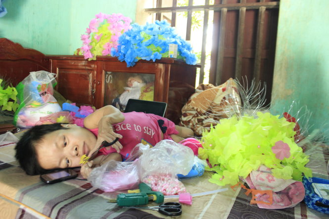 Bàn tay chị Nguyễn Thị Hòa tỉ mỉ cắt những cánh hoa giấy - Ảnh: N.NAM