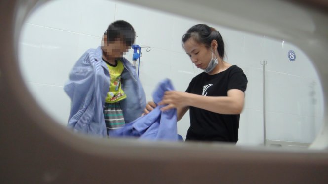 Chị Nguyễn Thị Hiền chăm sóc cho con bị bệnh sùi mào gà tại Bệnh viện Da liễu trung ương - Ảnh: DƯƠNG LIỄU