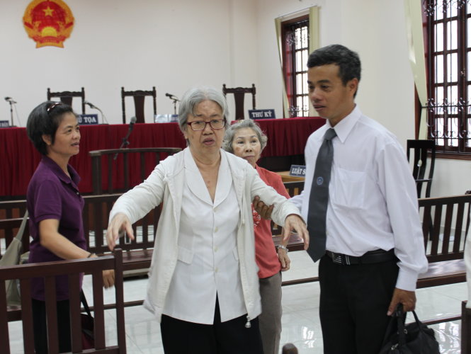 Bà Thơm được luật sư và người thân dìu về sau khi phiên tòa 
tạm hoãn - Ảnh: T.LỤA