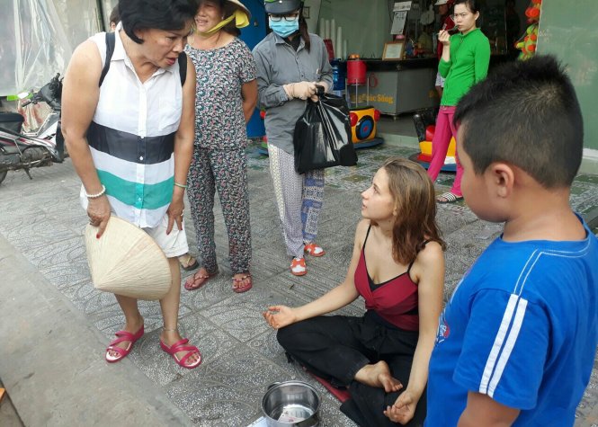 Người dân địa phương tỏ ra quan tâm trước 1 cô gái xinh xắn lại ngồi thiền để… xin tiền ngay trên vỉa hè - Ảnh: H.TRUNG