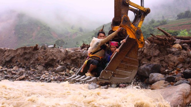 Anh Vàng A Tủa (21 tuổi, xã Ngọc Chiến) ôm vợ con ngồi máy cẩu liều mình qua suối để đưa vợ xuống bệnh viện - Ảnh: HÀ THANH