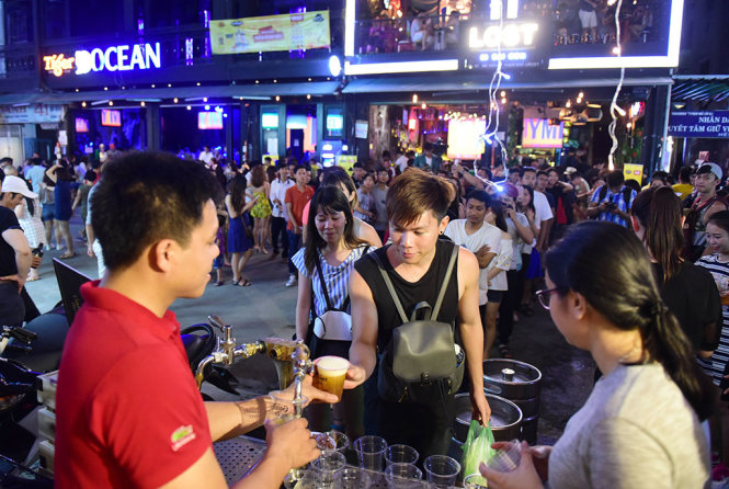 Hàng dài người xếp hàng chờ lấy bia tại phố đi bộ Bùi Viện - Ảnh: HỮU THUẬN