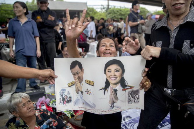 Những người ủng hộ đem theo hình anh em nhà Shinawatra ra trước Tòa án tối cao ở Bangkok khi đi ủng hộ bà Yingluck - Ảnh: AFP