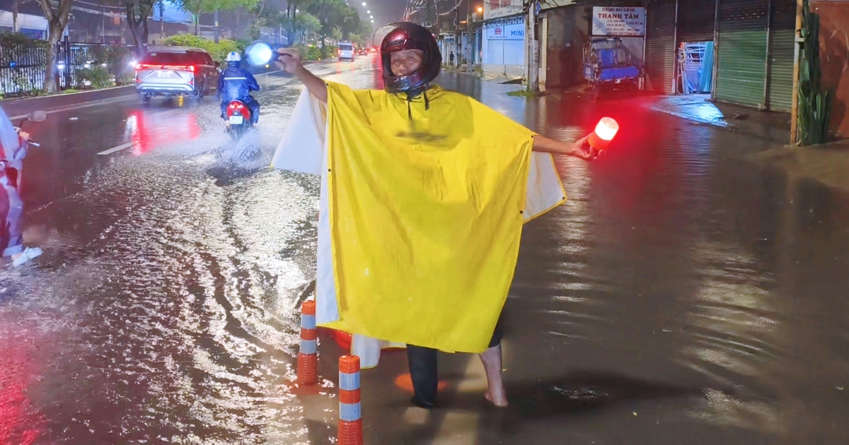 Người đàn ông ở TP.HCM bì bõm trong đêm hướng dẫn xe tránh đường ngập
