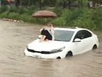 Cô gái cầm ô ngồi trên nóc ca pô giữa 'biển nước' ở Hà Nội