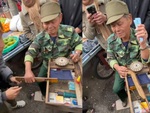 Cụ ông không cho chàng trai đặt súng khi chơi trò bắn vịt nhựa du xuân