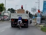 Thanh niên đi xe đạp bám đuôi ô tô tải để tránh gió