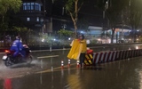 Ông Nguyễn Đắc Lắc mặc áo mưa lội nước, hướng dẫn xe qua đoạn đường ngập ở TP.HCM