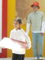 Cô bé vui mừng cầm bảng thưởng chạy về chia sẻ niềm vui với bà