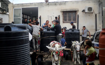 Người đàn ông và chú lừa kéo xe đi phân phát nước ở Dải Gaza
