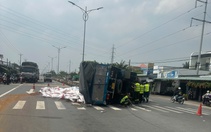 Xe tải lật chắn ngang, hàng chục bao thức ăn thủy sản tràn xuống đường