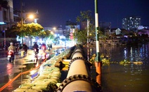 Đắp bao cát ngăn nước kênh Tẻ tràn vào đường Trần Xuân Soạn khi triều cường