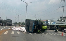 Xe tải lật chắn ngang, hàng chục bao thức ăn thủy sản tràn xuống đường