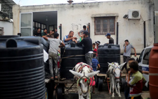 Người đàn ông và chú lừa kéo xe đi phân phát nước ở Dải Gaza