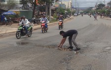 Người đàn ông cặm cụi nhặt đá lấp một ổ gà