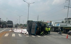 Xe tải lật chắn ngang, hàng chục bao thức ăn thủy sản tràn xuống đường