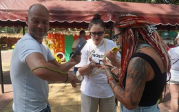 Du khách dạn tay ôm rắn chụp hình tại Trại rắn Đồng Tâm