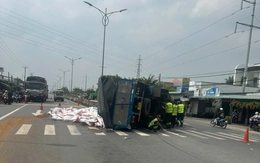 Xe tải lật chắn ngang, hàng chục bao thức ăn thủy sản tràn xuống đường