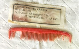Chiếc lược đỏ và tấm giấy ép plastic trong ngôi mộ in dòng chữ: Liệt sĩ Nguyễn Văn Dục, quê Hà Tây
