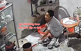 Bé trai dùng đá mài gõ để gỡ hai cái tô dính nhau