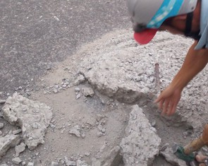 Hai thợ nề đục đẽo dẹp khối bêtông đổ giữa đường để xe không tai nạn