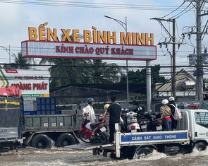 Cảnh sát giao thông dùng xe chuyên dụng đưa dân qua điểm ngập sâu trên quốc lộ 1 ở Vĩnh Long