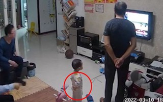 Bé trai bắt chước ông đứng chắp tay sau lưng xem tivi