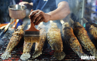 Charcoal burns overnight as vendors prepare grilled snakehead fish for God of Wealth Day in Ho Chi Minh City