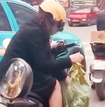 Người phụ nữ tranh thủ lặt rau lúc dừng chờ đèn đỏ gây 'sốt' mạng xã hội