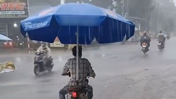 Chàng trai lấy dù size đại che mưa siêu lầy