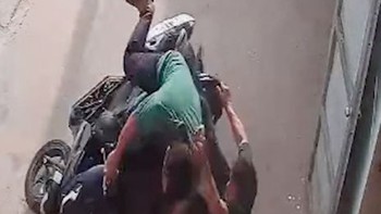 Người đàn ông khổ sở với bạn say rượu không leo nổi lên xe máy