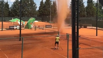 Chàng trai dùng vòi nước xua đuổi vòi rồng trên sân tennis