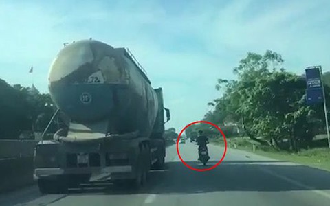 Thanh niên đầu trần bám theo xe bồn để núp bóng tránh nắng