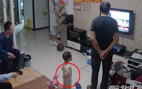 Bé trai bắt chước ông đứng chắp tay sau lưng xem tivi