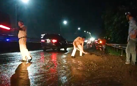 Cảnh sát giao thông và người dân dọn đất đá trên quốc lộ 1 sau mưa lớn