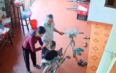 Ông cho cháu ngồi xe đạp đi quanh sân để bà bón cơm