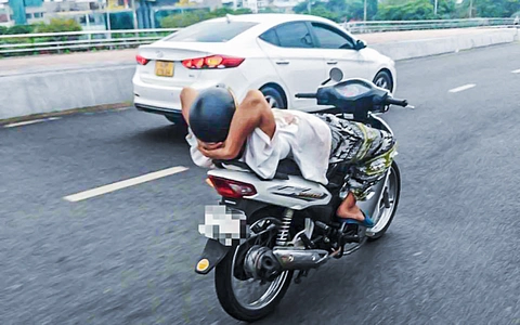 Người đàn ông 39 tuổi thả 2 tay, nằm ngửa trên xe máy chạy qua cầu Rồng