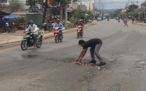 Người đàn ông cặm cụi nhặt đá lấp một ổ gà