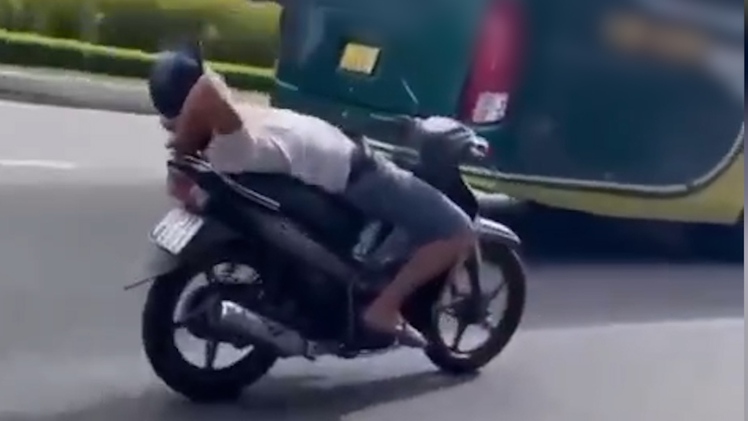 Người đàn ông thả 2 tay, nằm ngửa trên xe máy chạy qua cầu Rồng là ai?