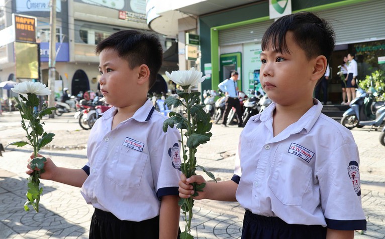 Người dân cầm hoa trắng đợi tiễn đưa các anh