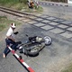 Người đàn ông chạy xe máy mải nghe điện thoại tông barie chắn tàu